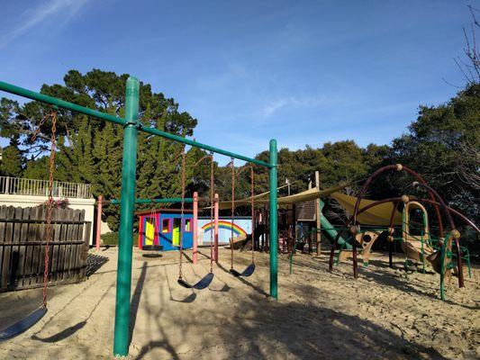 Huge sand play area with swings, climbers, and play house.