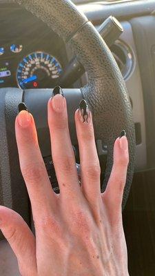 Acrylic nails with black tips and black flames on the ring fingers.