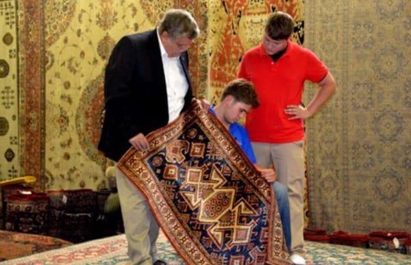 NYRug Authority owner Robert Deacon along with his sons Robert and Jake. Here we're admiring a beautiful hand knotted silk rug.