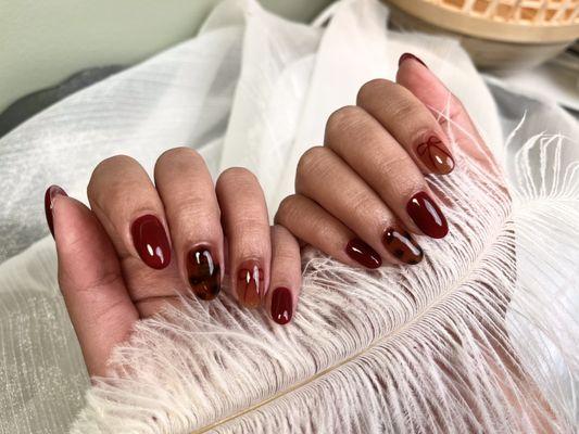 dark cherry red nails with tortoise design and detailed bow design