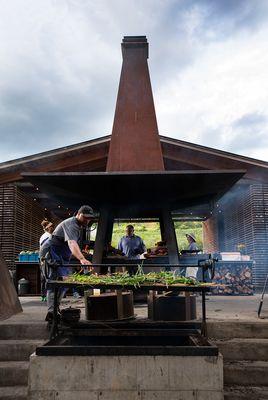 Chefs working around the Motherfire, our 30ft tall custom-built cooking hearth.