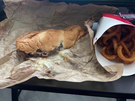 Sloppy French dip with more than half the cheese stuck on soggy paper and half a large fry.