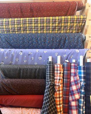 Apparel fabric wall of rayon dress fabrics, plaids for jackets and button-up, tencel twill wovens for pants, jackets, dresses, skirts.