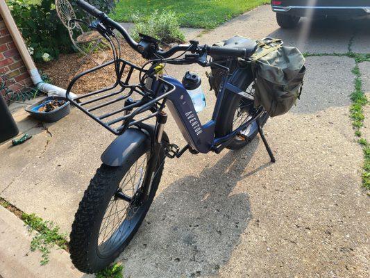 Aventon Aventure 2 midnight blue fat tire ebike with front and rear racks and big army green panniers.