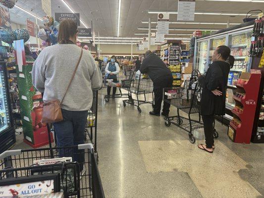 People waiting in line with only 2 check stands open during rush hour.