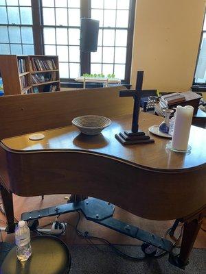 Piano with cross next to podium with bibles