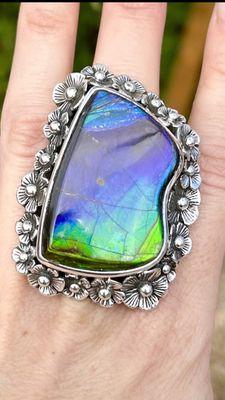 Amazing stacked silver flowers on an Ammolite stone which is an ammonite fossil.