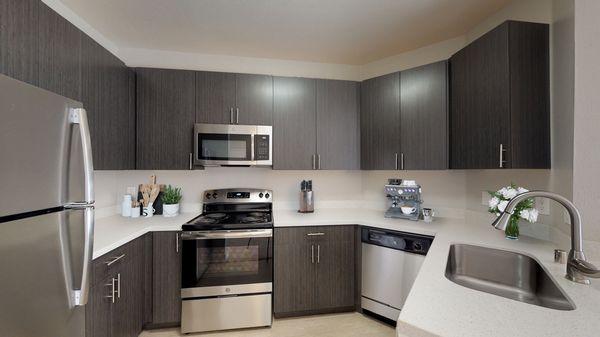 Spacious kitchen with hardwood-style vinyl floors, stainless steel appliances, and quartz countertops.