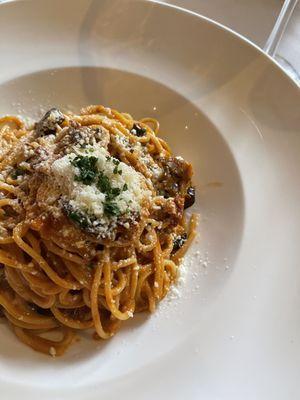 Pasta with mushrooms and pancetta in a red sauce with a touch of cream.