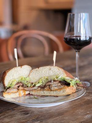 Lan Roc pork belly sandwich with piquillo aioli, pickled cucumber, aged provolone, shredded lettuce on a dos hermanos bolillo