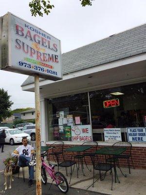 Shot of the entrance of the bagel shop, there is outdoor seating.