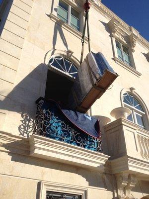 Hoisting a baby grand piano with a little assistance from a crane