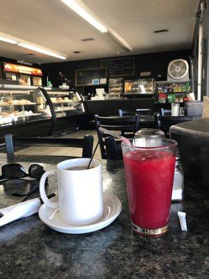 Cafe con Leche y Jugo de Mora en Agua. En el fondo una vista de la vitrina con dulces.