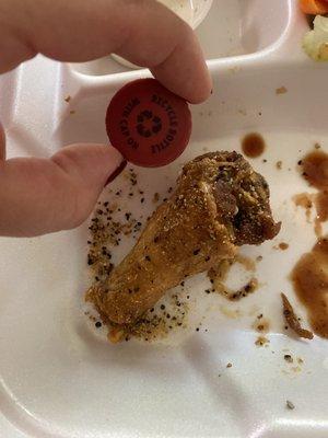 Bone in Lemon Pepper wing next to a bottle cap