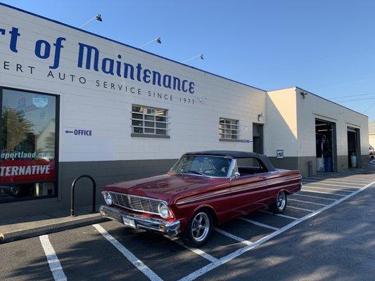 A classic Falcon parked in front of the main building that contains the waiting area, offices, and a couple bays for cars.