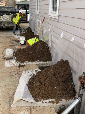 Preparing to install push piers around a home.