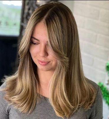 full head of hilites with a shadow root and shades toner also a layered haircut with curtain bangs and a soft wavy blow-dry