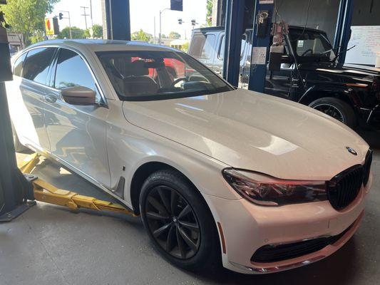 A 7 series BMW in a rotary lift in bay two about to be lifted for inspection