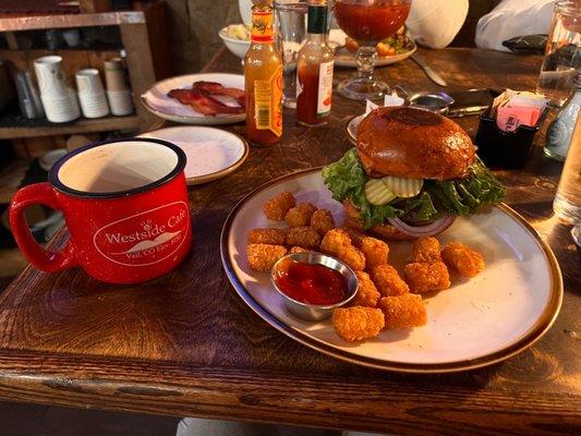 Coffee, and a burger with bacon, pickles, onion, lettuce, pepper-jack cheese, tomatoes and tater tots on the side.