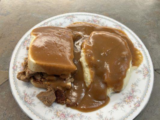 Hot beef dinner served open faced on sourdough bread with mashed potatoes and delicious brown gravy