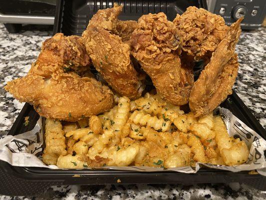 Fried chicken wings and seasoned french fries.