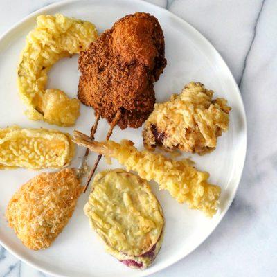 A variety of freshly fried Tempura. Clockwise from upper left: pumpkin, katsu, chicken, shrimp, sweet potato, dish, and egg