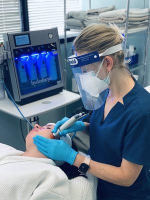 Daria performing a hydrafacial with her Patient/Personal Protective Equipment gear on.