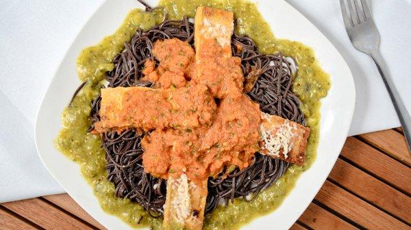 Pan-seared Tofu Steaks shown on a nest of Black Bean Pasta (GF) under an España Salsa el Fresca surrounded by Cilantro Pesto.