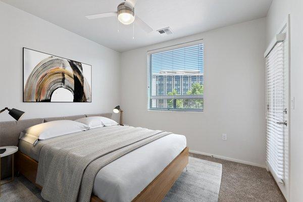 Large bedroom with ceiling fan lighting and plush carpet flooring.