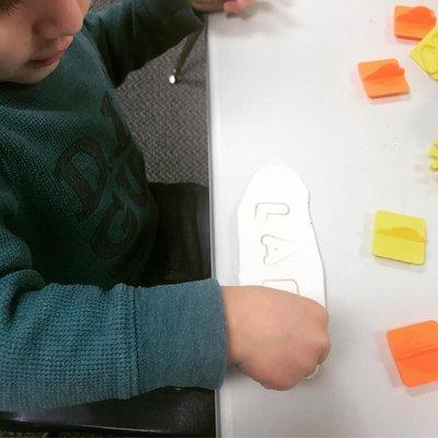 Learning our names by stamping playdough.