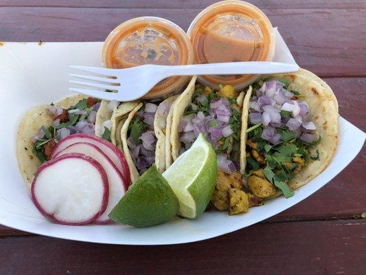 Pastor tacos (left) and chicken tacos (right) with red onions and the strange fuego sauce.