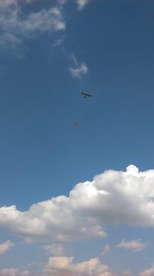 A flyer pulls the hand glider up into the air. It soon releases.