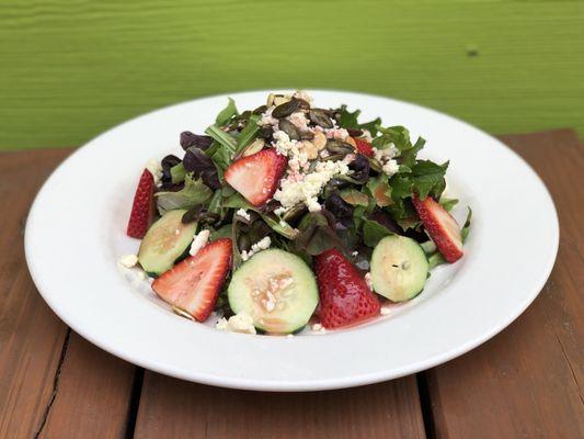 Spring salad, spring mix with cucumber, strawberries, pepita seeds and queso fresco with a vinaigrette.