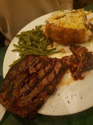 Rib-eye steak with green beans and loaded baked potato