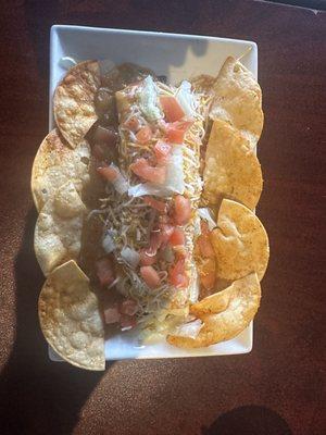 A Smothered Burrito with homemade chips, smothered in Green Chile, Cheese & tomatoes.