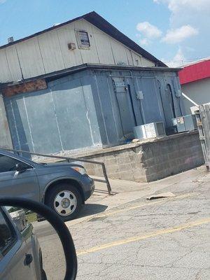 Cooler behind restaurant. Rusting, falling apart, boarded up with a massive gap on the side