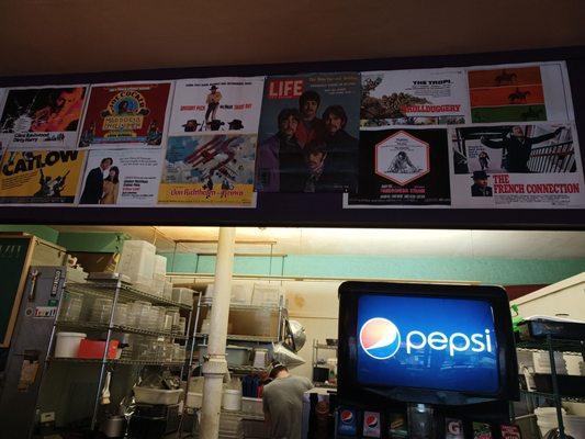 Cool circa 60s and early 70s posters adorn the wall with a cutout view of the kitchen.