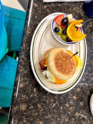 Breakfast sandwich and fruitbowl.