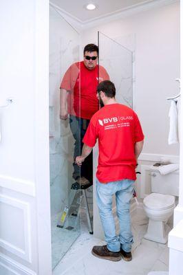 Installation team installing new glass shower door.