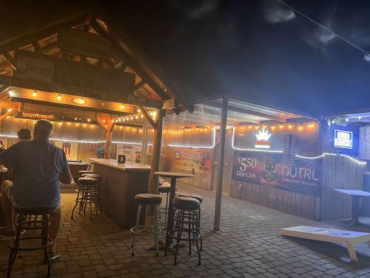 Outdoor patio has a pool table, cornhole and lots of seating