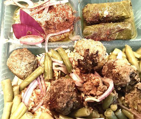 Combination rice plate with meatballs, green beans, cooked with garlic and tomato, stuffed grape leaves, and hummus.