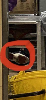 Photo clearly shows the shoe and hand of employee sleeping while the store was wide open.