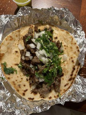 Beef fajita taco with onion and cilantro on flour tortilla.