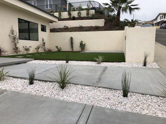 pink gravel, concrete walkway, stucco mailbox, synthetic grass, and planting