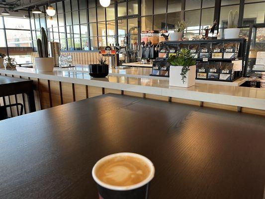 View of part of the coffee bar in the back and a cortado in the front.