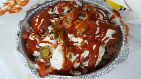 Falafel over spicy rice with white sauce, hot sauce and jalapeno