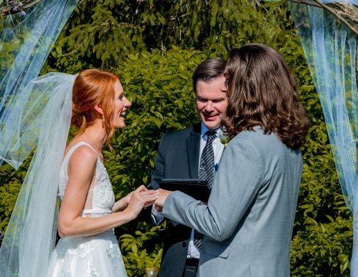 Wedding photo of couple putting rings on at the alter.