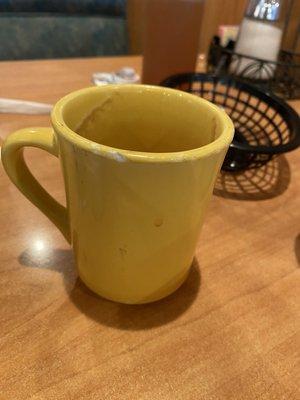 Dirty coffee cup with chips in the lip area.