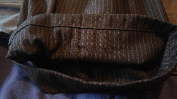 The inside hem on the pants of his suit.