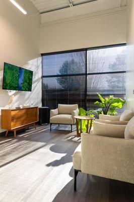 Exam room at Vertrae® with sofa chairs, large windows, and television